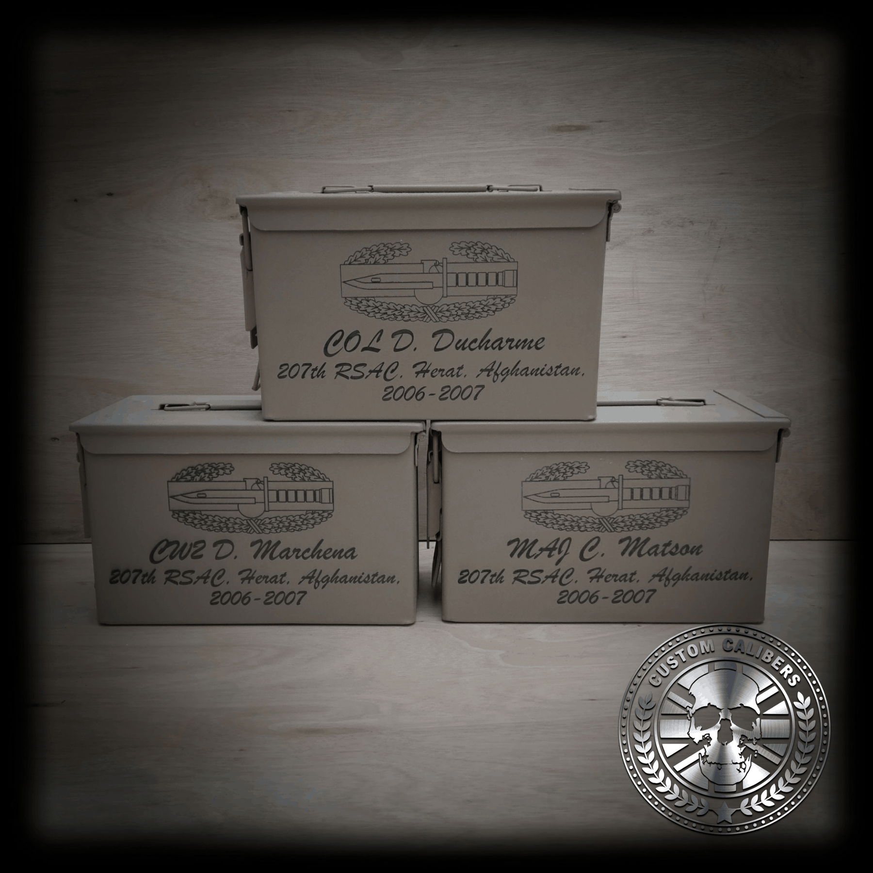 A picture of three boxes with engravings on them and the custom calibers logo at the bottom right