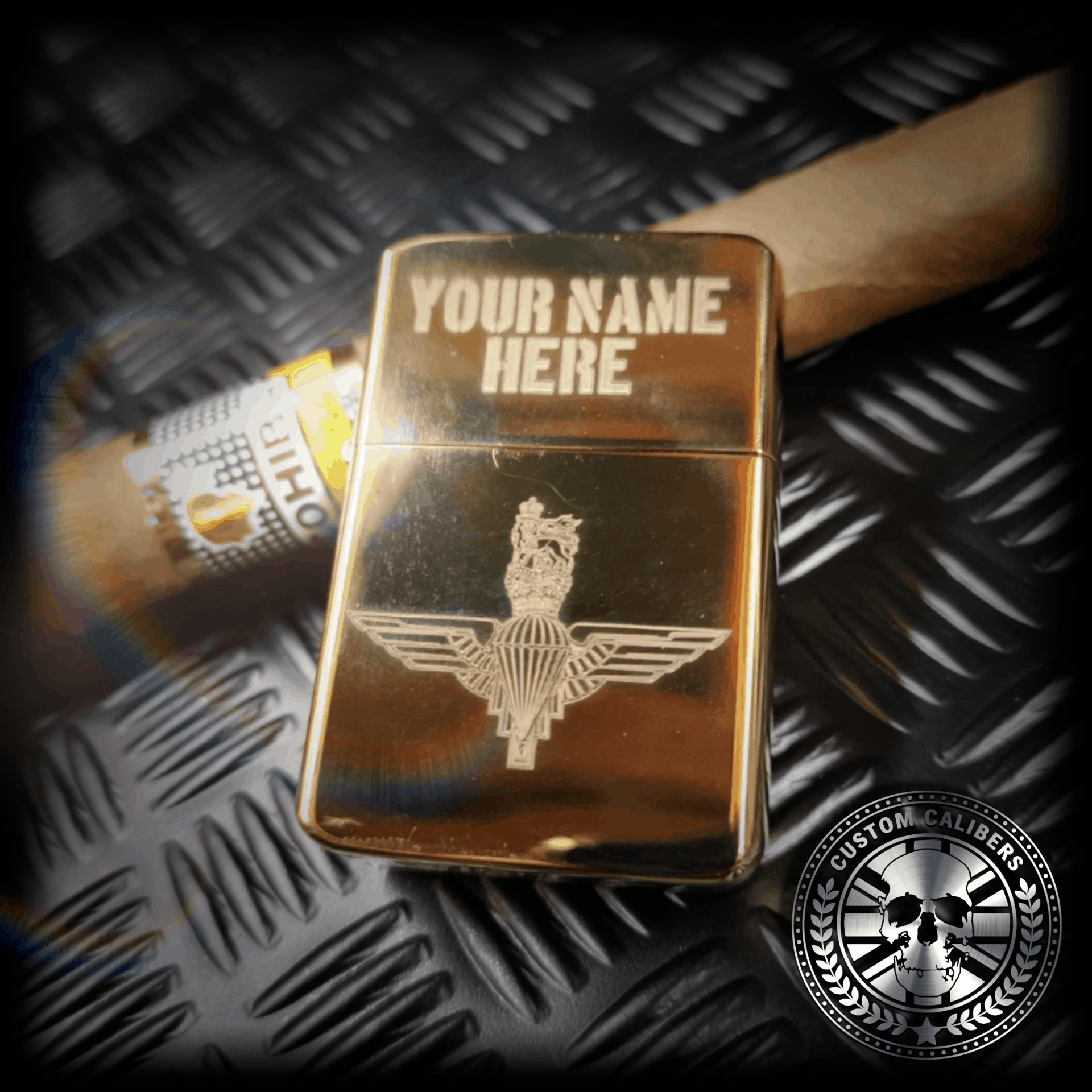another shot of a gold coloured solid brass lighter engraved with the parachute regiment crest resting on a large cuban cigar