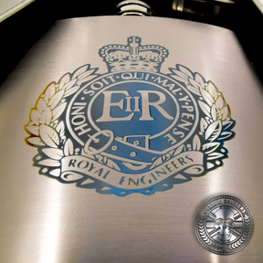 close up photo of a brushed stainless steel hip flask engraved with a military crest