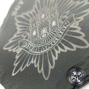 a close up of an engraved slate coaster with the royal anglian regiment crest