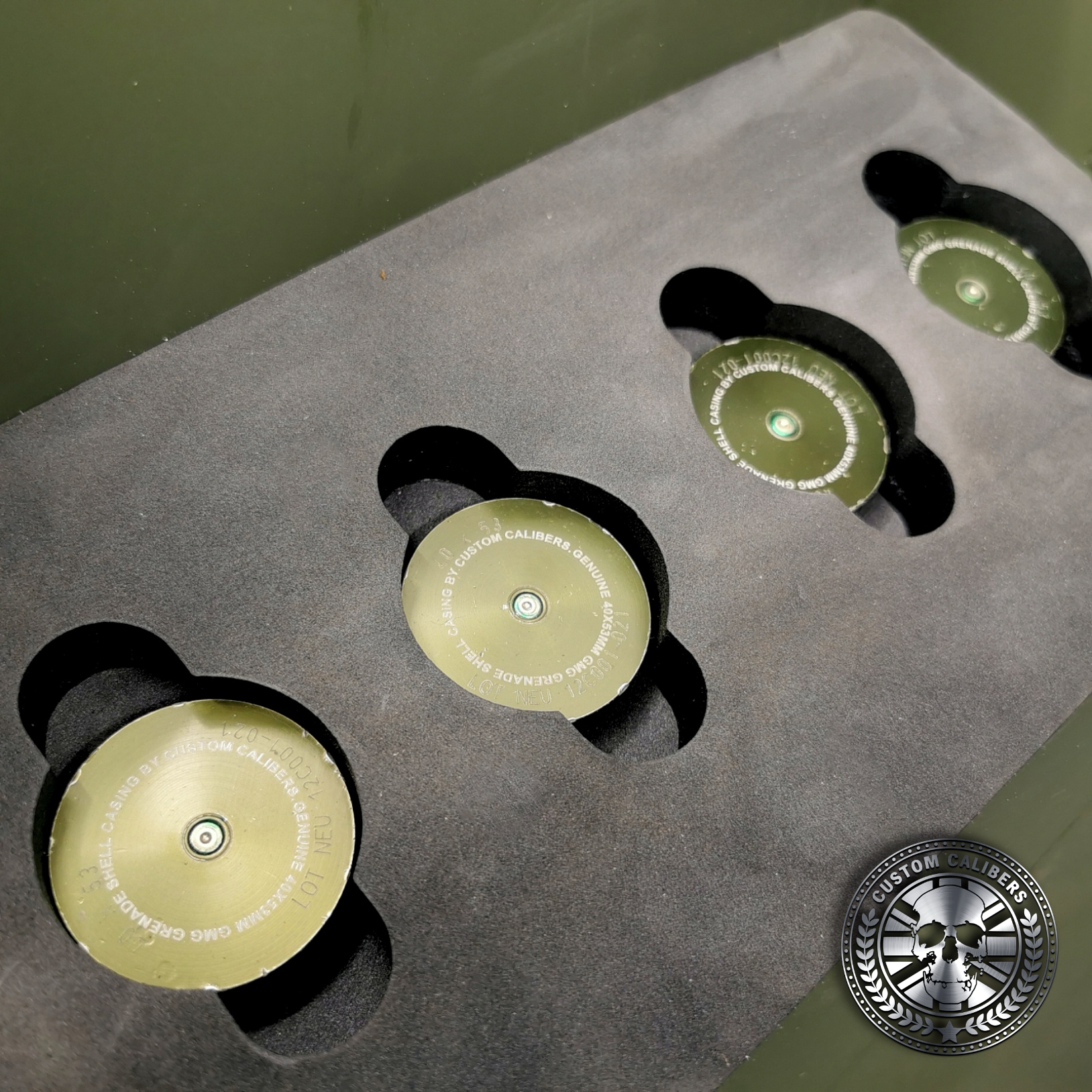 four 40mm grenade shot glasses sitting inside cut foam